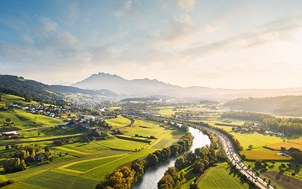 Landschaftsbild mit Fluss, Strassen, Landwirtschafts- und Siedlungsflächen in der Schweiz.